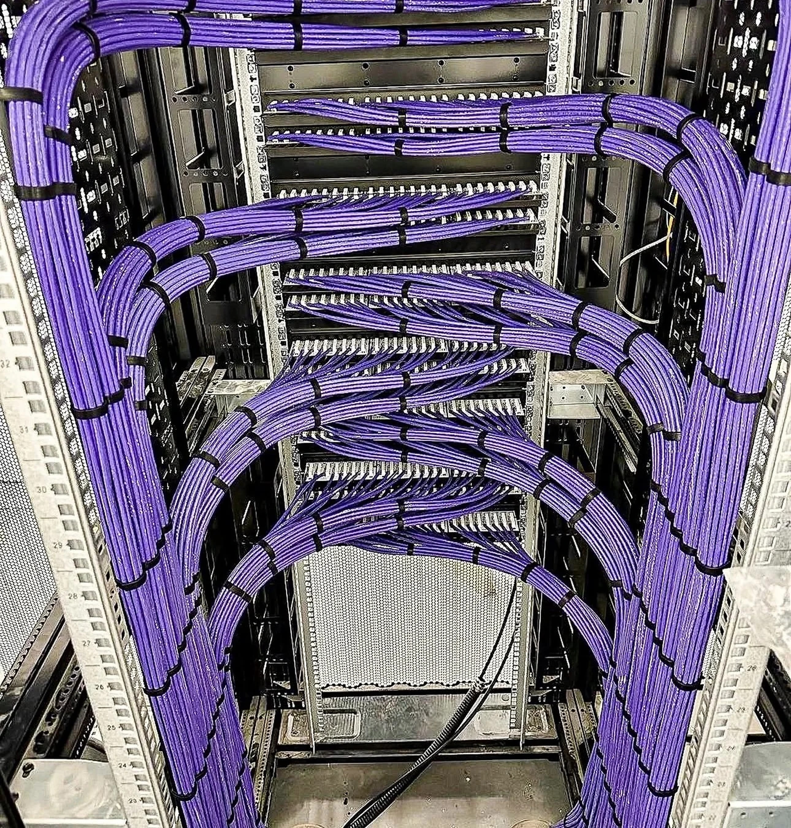 Real commercial network rack with organized purple patch-panel cabling