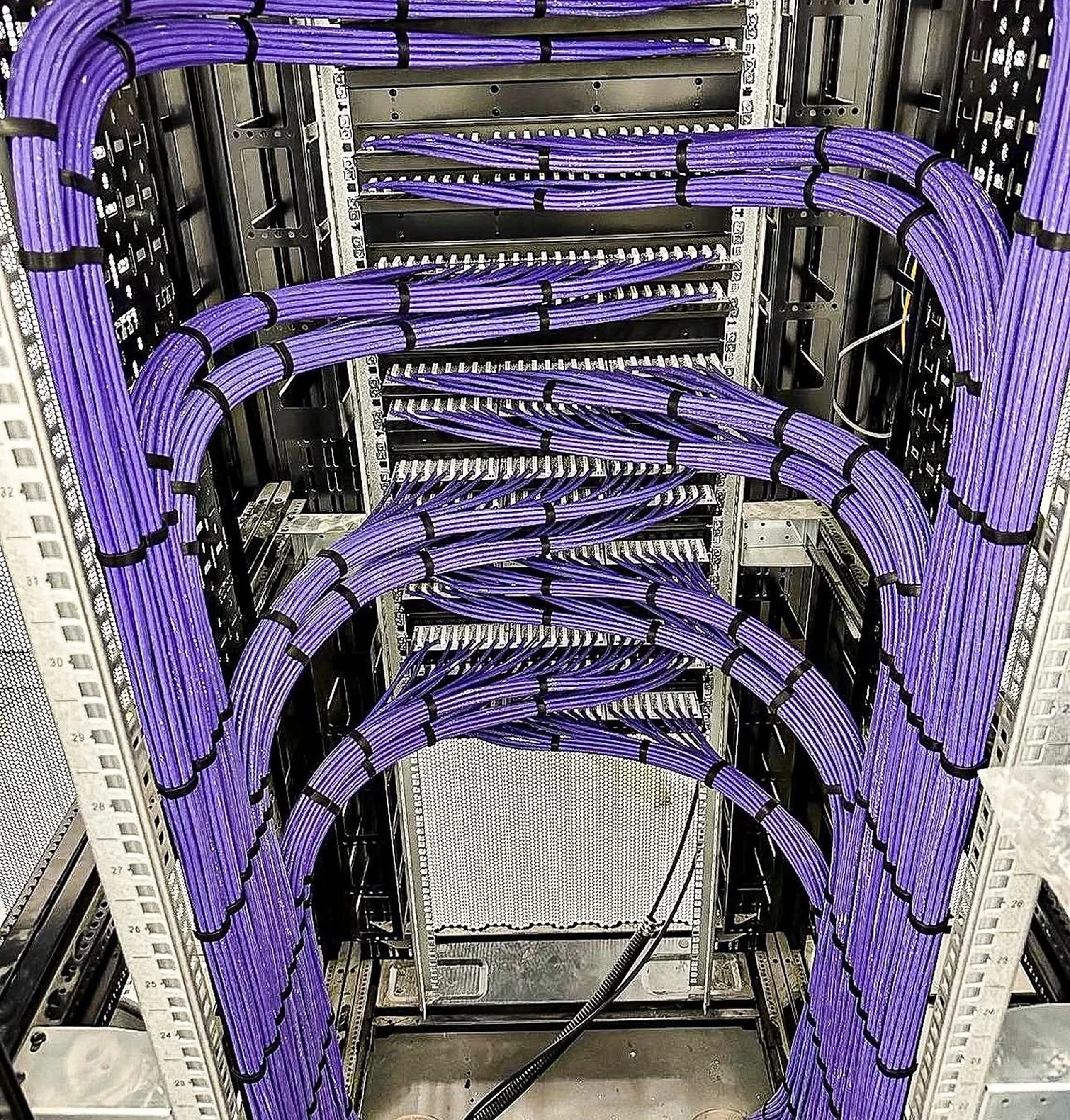 Commercial network rack with organized purple patch-panel cabling